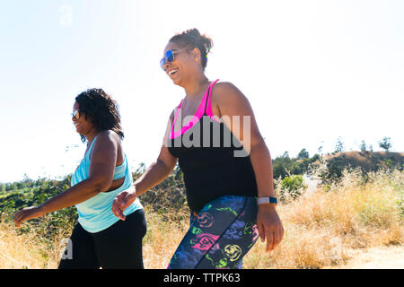 Low Angle View von Happy weibliche Freunde gehen auf gegen den klaren Himmel Stockfoto