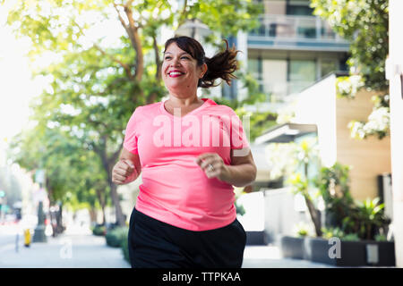 Fröhliche Frau joggen auf Wanderweg in Stadt Stockfoto