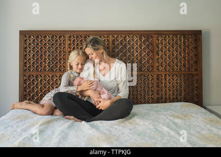 Mutter und Tochter bei neugeborenen Babys beim Sitzen auf dem Bett Stockfoto