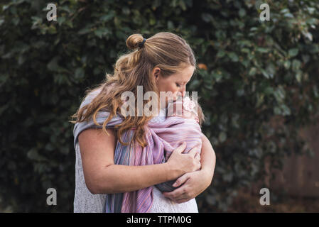 Mutter küssen neugeborenen Tochter, während im Hinterhof stand Stockfoto