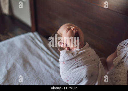 Mittelteil der Mutter, Neugeborenes gähnen Tochter auf dem Bett zu Hause. Stockfoto