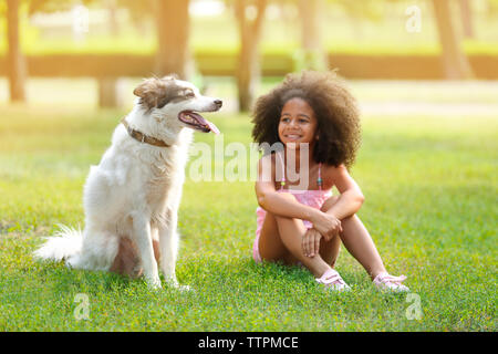 Cute Afrikanische amerikanische Mädchen spielen mit Hund im Park Stockfoto