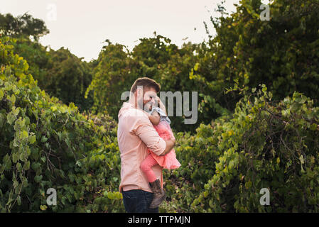 Seitenansicht der Vater die Tochter beim stehen inmitten von Pflanzen im Park Stockfoto