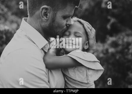 Nahaufnahme der Vater umarmt niedlichen Tochter beim Stehen in Park Stockfoto