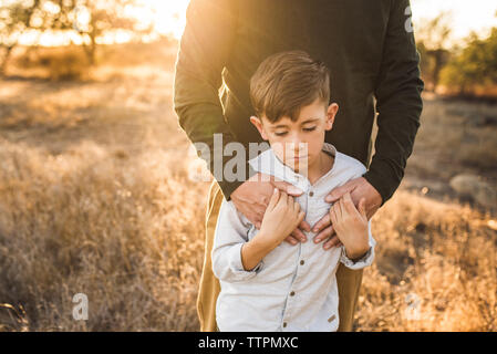 Nahaufnahme von Jungen durch Vater in Kalifornien Feld umfaßt wird Stockfoto