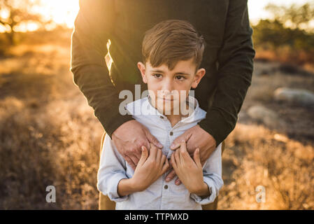 Nahaufnahme von Jungen durch Vater in Kalifornien Feld umfaßt wird Stockfoto