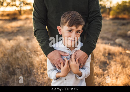 Nahaufnahme von Jungen durch Vater in Kalifornien Feld umfaßt wird Stockfoto