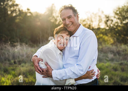 Senior Paar umarmen und außerhalb lächelnd in der Hintergrundbeleuchtung Stockfoto