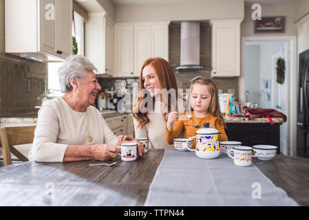 Mehr-generationen-Familie spielen mit Kaffee am Küchentisch gesetzt Stockfoto