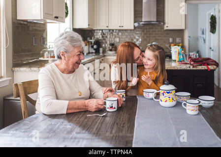 Mehr-generationen-Familie spielen mit Kaffee am Küchentisch gesetzt Stockfoto