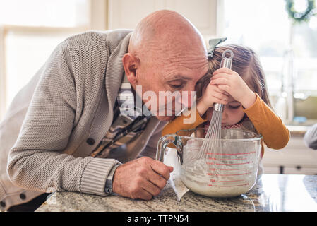 Opa helfen Enkelin kochen Pfannkuchen zum Frühstück Stockfoto