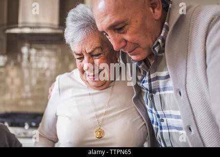 In der Nähe von erwachsenen Sohn umarmen senior Mutter in der Küche Stockfoto
