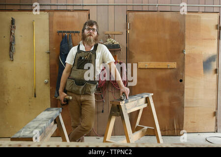 Portrait von zuversichtlich Tischler mit Arbeit Werkzeuge stehen in der Werkstatt Stockfoto