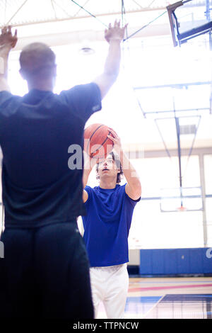 Männliche Basketball Spieler spielen in hell erleuchteten Hof Stockfoto