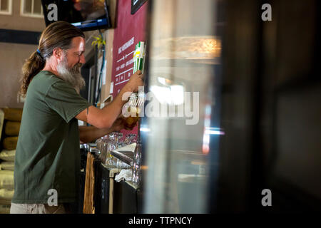 Seitenansicht der Barkeeper Bier aus Tippen Stockfoto