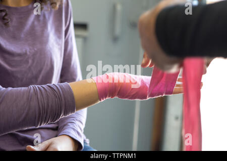 Zugeschnittenes Bild des Trainers Verpackung weiblichen Athleten hand mit Armband in der Turnhalle Stockfoto