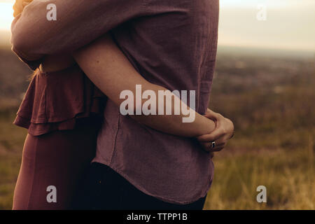 Seitenansicht der liebevollen jungen Paar, das auf dem Feld Stockfoto