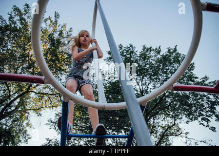 Low Angle View von Mädchen klettern an der Monkey Bars gegen Himmel am Spielplatz Stockfoto