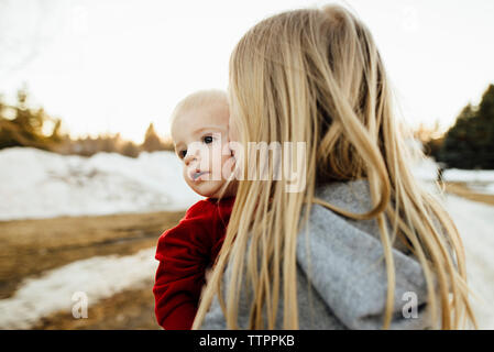 Mädchen küssen Bruder beim Stehen auf Feld im Winter Stockfoto