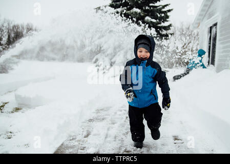 Happy Boy in warme Kleidung auf schneebedeckten Feld im Hof Stockfoto