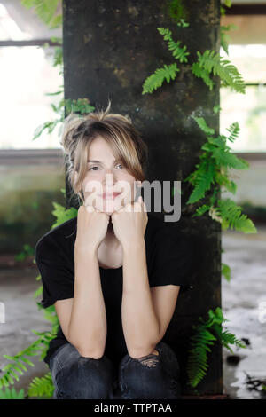 Portrait von selbstbewussten jungen Frau mit den Händen auf Kinn in alte Gebäude Stockfoto