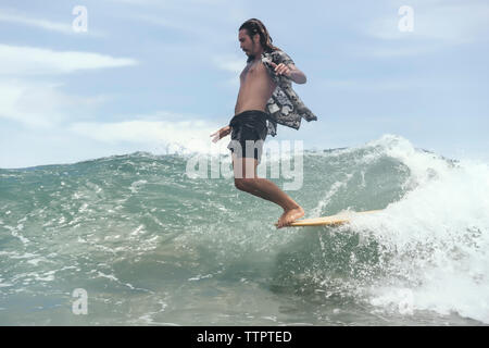 Man Surfen im Stehen am Surfbrett im Meer gegen Sky Stockfoto