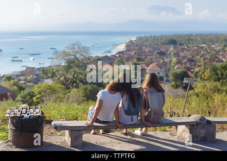 Ansicht der Rückseite des Freunde im Blick, während auf der Bank gegen Himmel sitzen Stockfoto