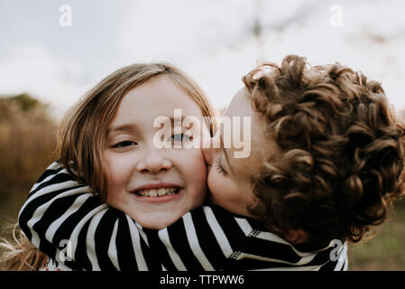 Close-up Portrait von lächelnden Schwester mit liebevoller Bruder sie Küssen im Park Stockfoto