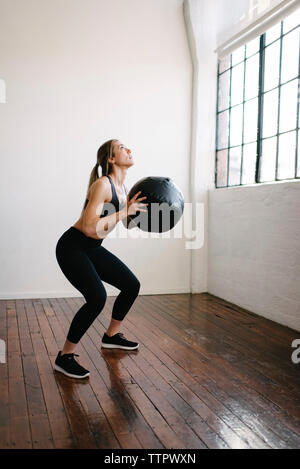 Weiblichen Athleten mit Fitness Ball beim Stehen in der Turnhalle Stockfoto