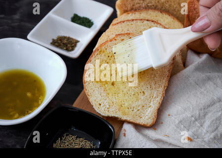 7/8 Finger der Frau die Butter auf geschnittenem Brot zu Hause Stockfoto