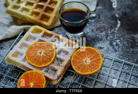 Hohe Betrachtungswinkel von Waffeln mit orangen und schwarzen Kaffee auf Tisch Stockfoto