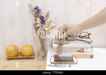 7/8 Hand halten Taste auf Bücher bei Tisch Stockfoto