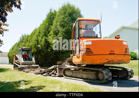 Arbeiter graben Land, während sie im Erdbeweger sitzen Stockfoto