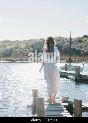 Rückansicht der Frau stehen auf hölzernen Pier über Meer gegen den klaren Himmel während der sonnigen Tag Stockfoto