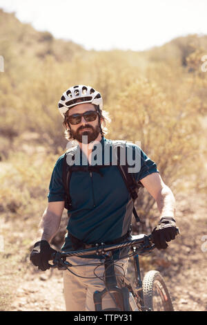 Portrait von zuversichtlich Biker stehen mit dem Fahrrad auf Berg Stockfoto