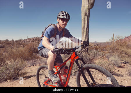 Sicher Mann reiten Mountainbike auf Landschaft gegen blauen Himmel Stockfoto