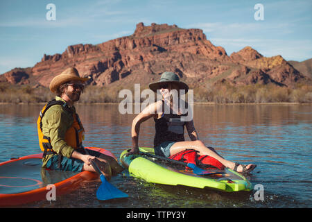 Glückliches Paar sitzt auf paddleboards am See Stockfoto