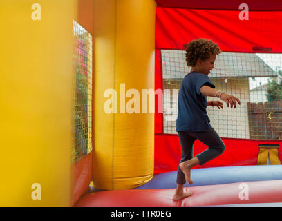 Seitenansicht der glücklichen jungen Springen auf hüpfburg im Park Stockfoto