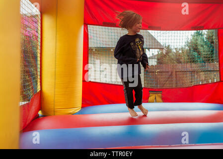 Happy girl auf der Hüpfburg im Park springen Stockfoto
