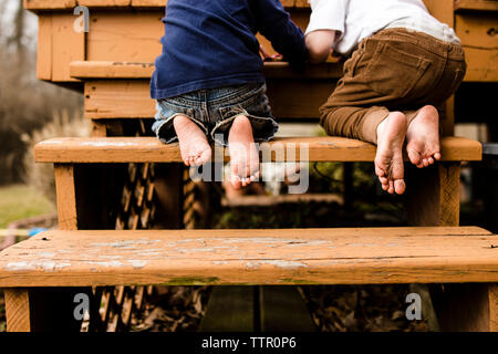 Niedrige Abschnitt der Brüder spielen, während Sie auf die Schritte am Spielplatz kniend Stockfoto