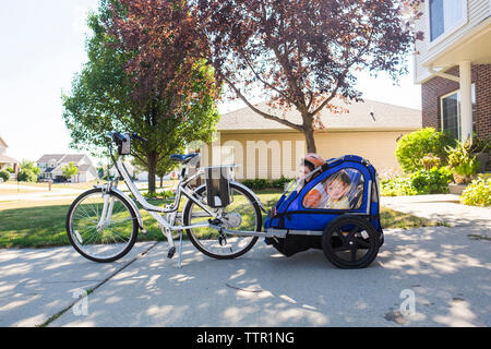 Brüder in Fahrrad Anhänger sitzen auf Fußweg Stockfoto