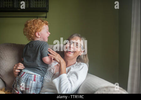 Verspielte Großmutter und Enkel auf einen Sessel zu Hause sitzen Stockfoto