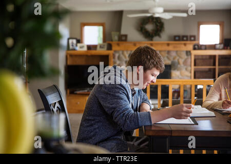 Seitenansicht des jungen Mannes Studium am Tisch zu Hause Stockfoto