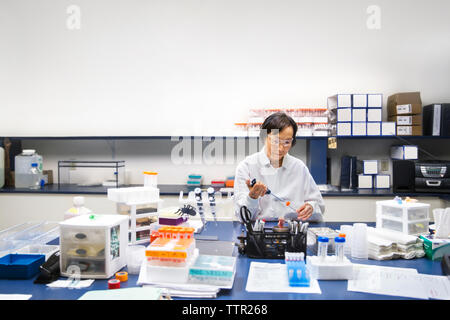 Leitende Wissenschaftlerin mit Pipette während Experiment im Labor Stockfoto