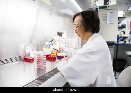 Seitenansicht der leitenden Wissenschaftlerin mit Pipette während Experiment im Labor Stockfoto