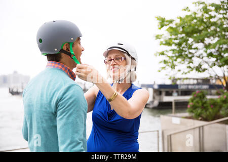 Reife Frau Unterstützung der Mann in tragen Fahrradhelm gegen den klaren Himmel Stockfoto