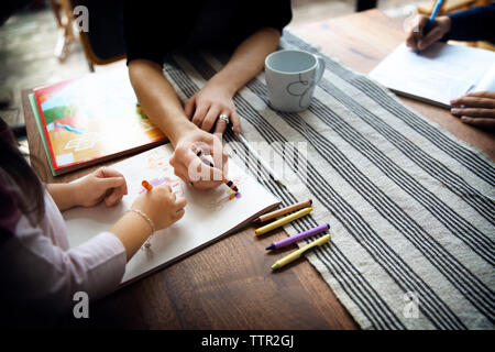 Hohe Betrachtungswinkel von Mutter Lehre Zeichnen zur Tochter auf Tisch Stockfoto