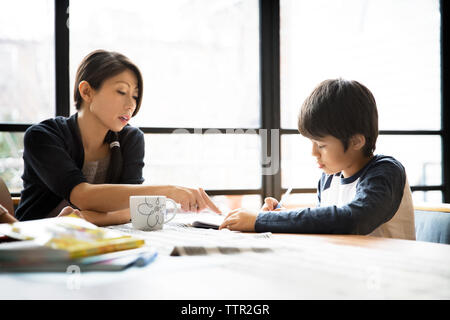 Mutter, Sohn in Hausaufgaben auf Tisch Stockfoto