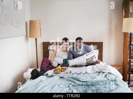 Multi-ethnischen homosexuelle Männer lesen Zeitung im Schlafzimmer Stockfoto
