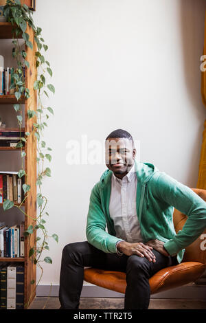 Portrait von zuversichtlich gay Mann auf Stuhl zu Hause sitzen Stockfoto
